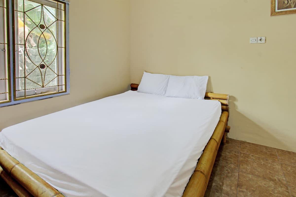 A room with a bed, a window with a decorative design, and a light switch on the wall.