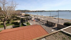 A coastal marina with a clear view of the water, a parking area, and a building with a red-tiled roof. - Charming Mezzanine T1, A/C, Thau View (Balaruc-les-Bains)