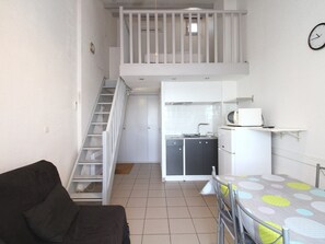 A compact living space with a kitchenette, a dining area, and a staircase leading to an upper level. - Charming Mezzanine T1, A/C, Thau View (Balaruc-les-Bains)
