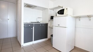 A compact kitchen with a white refrigerator, a microwave, and a sink. - Charming Mezzanine T1, A/C, Thau View (Balaruc-les-Bains)