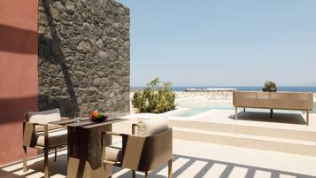 Una terraza con mobiliario de mimbre, un muro de piedra y vista al mar.