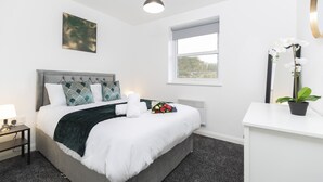 Une chambre à coucher moderne avec un lit, une table de chevet, une fenêtre et une plante en pot.