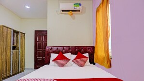 Ein Hotelzimmer mit einem Bett, einem Kleiderschrank, einer Tür, einer Klimaanlage und einem fenster mit Vorhängen.