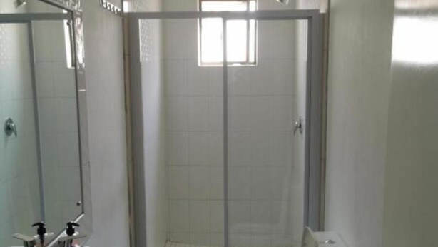 A bathroom with a shower, toilet, sink, and mirror. - White House Guesthouse 29Kew (Johannesburg)
