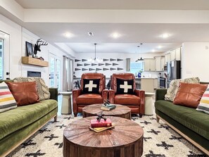 Un salon moderne avec des canapés verts, des fauteuils en cuir et une table basse en bois.