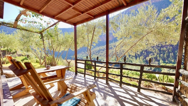 A wooden deck with chairs and a table, overlooking a mountainous landscape. - Dar l'eau vive (Bine el Ouidane)