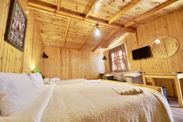Um quarto com painéis de madeira, uma cama, uma escrivaninha, uma televisão e uma janela com cortinas.