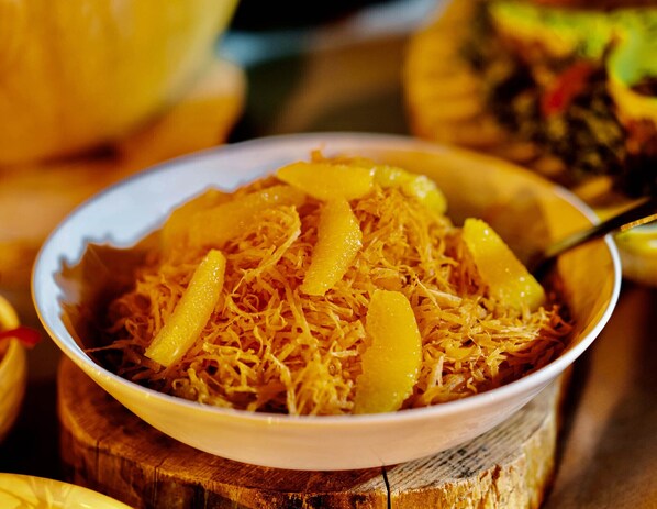 A bowl of shredded yellow food, possibly a dish with citrus elements, on a wooden surface. - Dar l'eau vive (Bine el Ouidane)