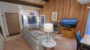 Un salon confortable avec un canapé, une table avec une lampe, un téléviseur et une cheminée.