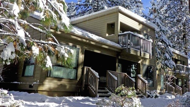 Un bâtiment à deux étages doté d’un balcon au deuxième étage, entouré d’arbres couverts de neige.