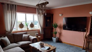 A cozy living room with a sofa, a wooden coffee table, and a television. - 3-bed Apartment in Lowestoft With sea Views (Lowestoft)