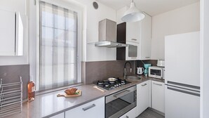 Una cocina moderna con estufa a gas, horno, microondas y una ventana con persianas.