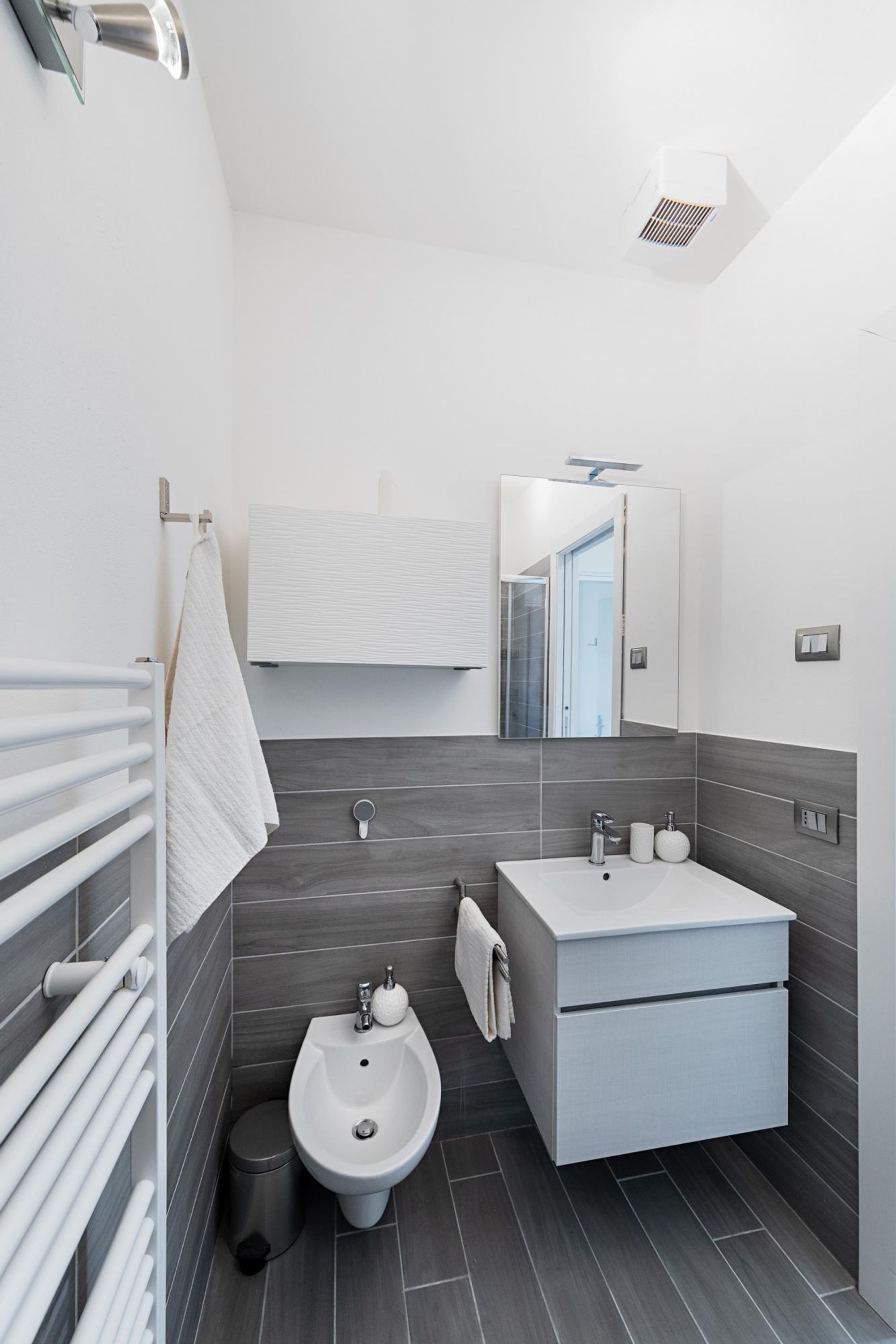 Une salle de bain moderne équipée d’un bidet, d’un lavabo et d’un miroir.