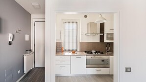 Una cocina moderna con armarios blancos, estufa a gas, horno y ventana con cortinas.