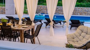 Eine Terrrasse im Freien mit Esstisch, Stühlen und einem Pool.
