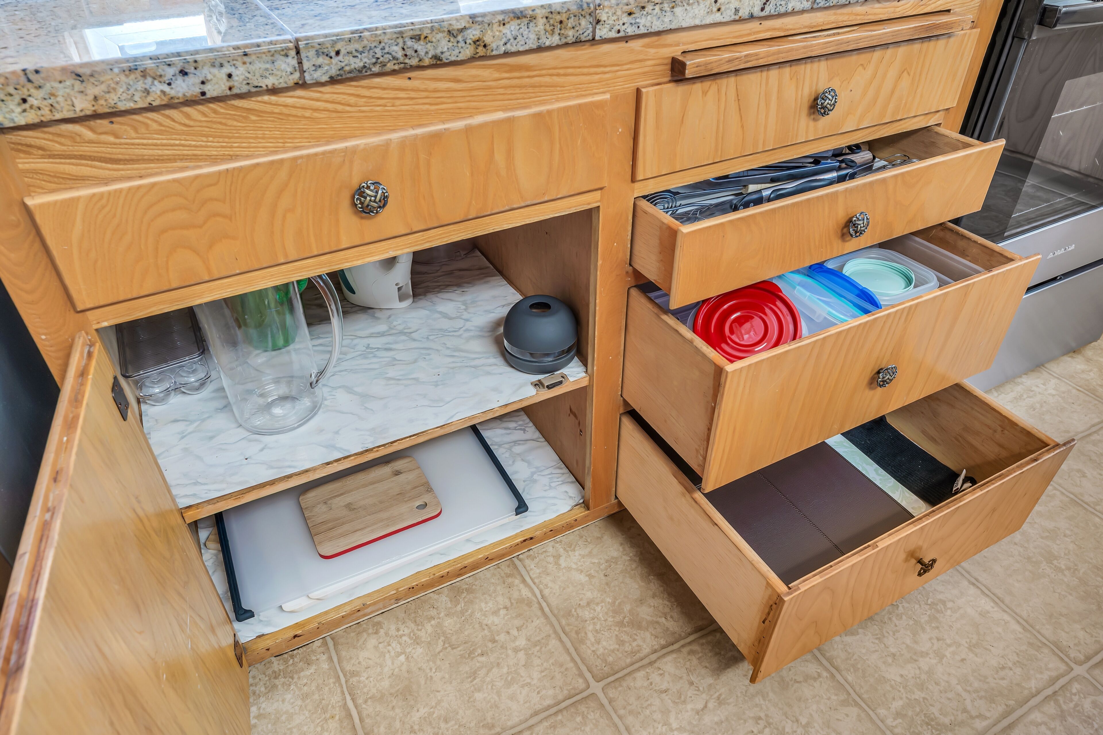 A kitchen with wooden cabinets, a marble countertop, and a stainless steel oven.