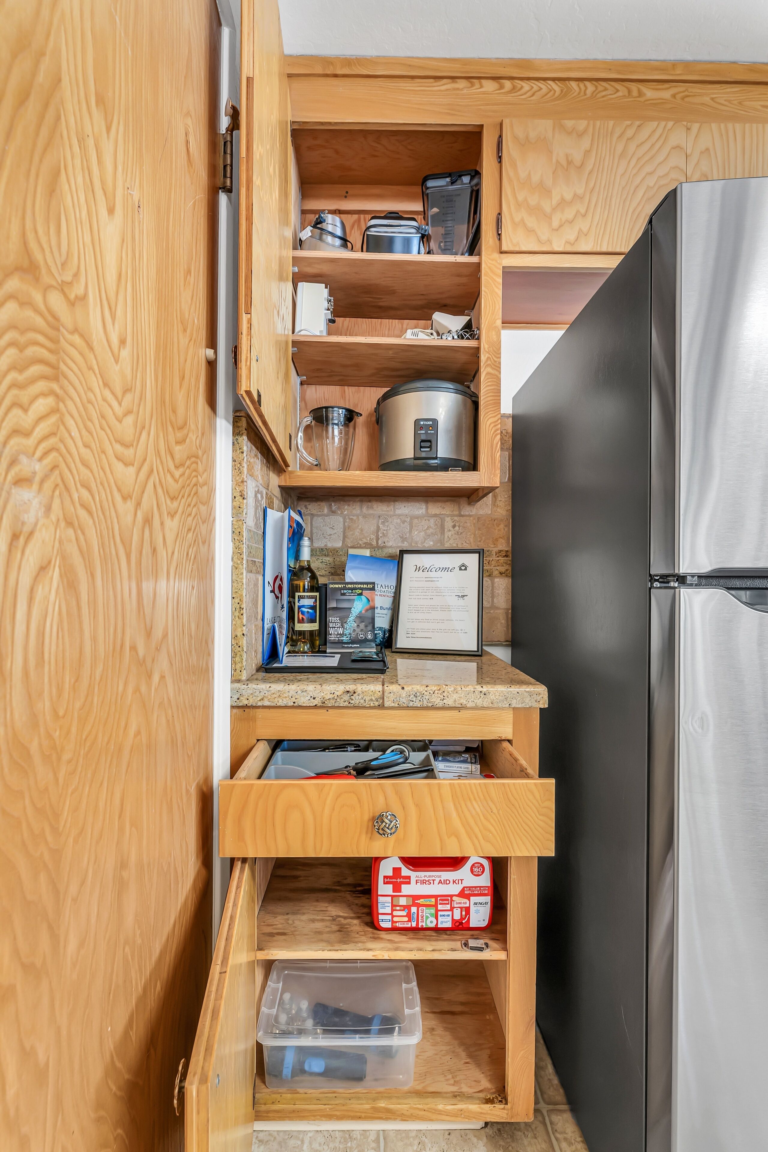 Eine Küche mit Holzschränken, einem Edelstahlkühlschrank und einem 'Welcome'-Schild.