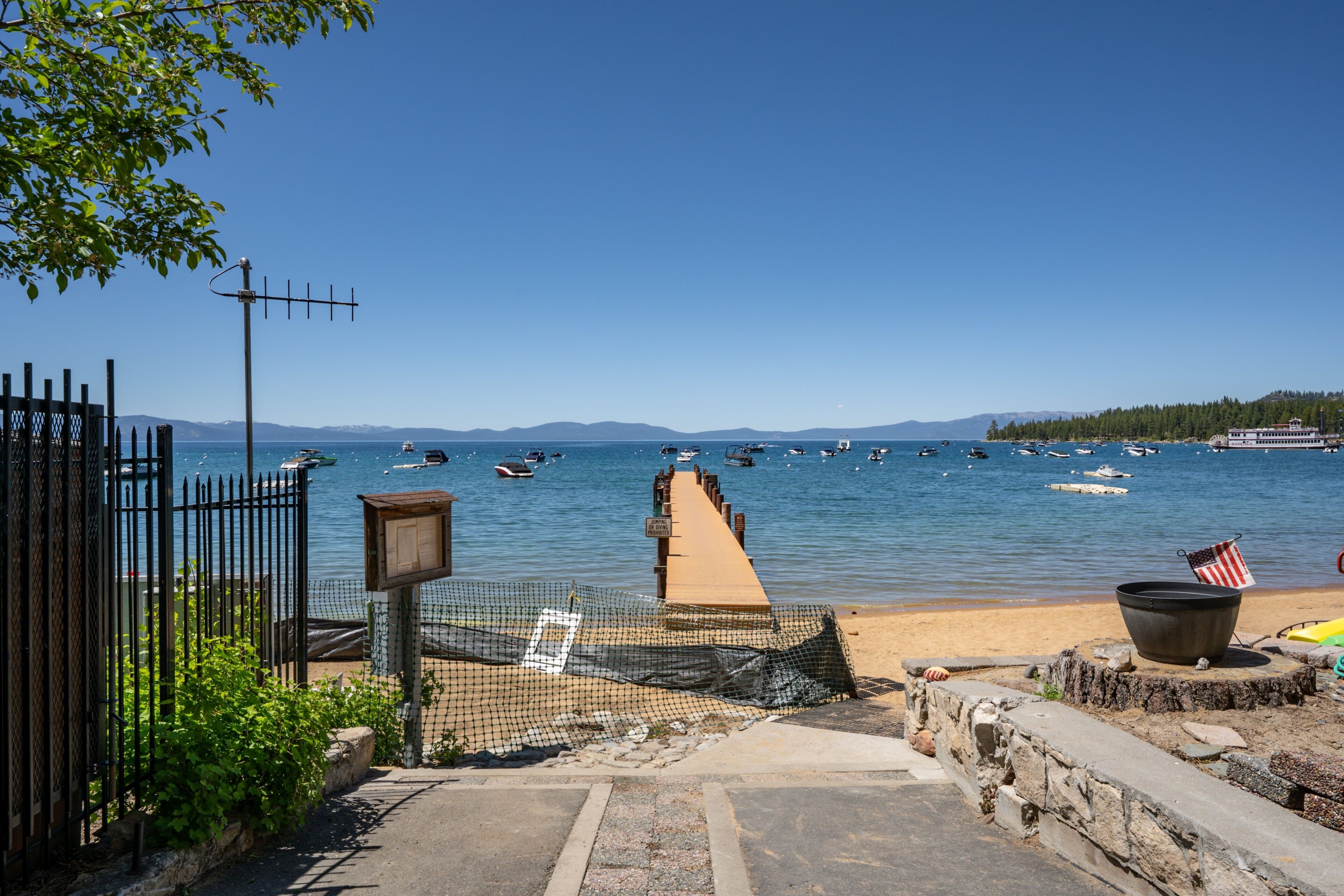 Vista de la playa con un muelle, barcos y cielo despejado.