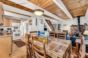 A spacious kitchen with wooden cabinets, a dining area with a glass table, and a cozy living room with a fireplace. - Cozy Mountain Hideaway 3 Bedroom Home by RedAwning (Incline Village)
