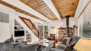 A living room with a fireplace, a sofa, a coffee table, and a TV. - Cozy Mountain Hideaway 3 Bedroom Home by RedAwning (Incline Village)