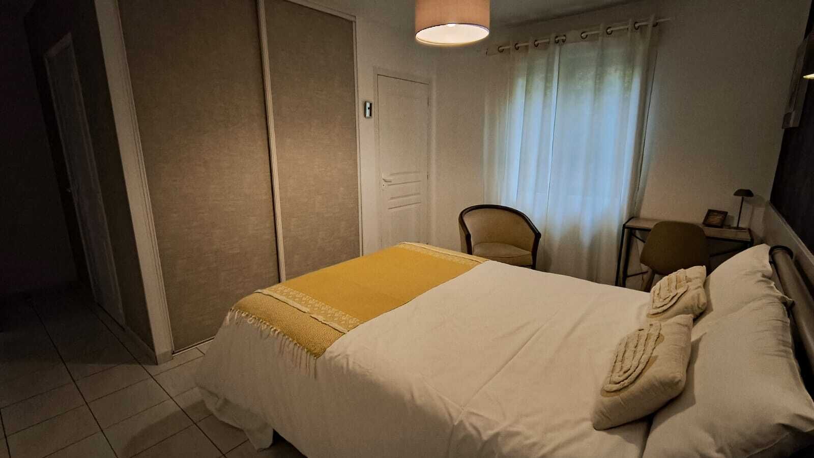 Una habitación de hotel con cama, una silla, un escritorio y una cortina.