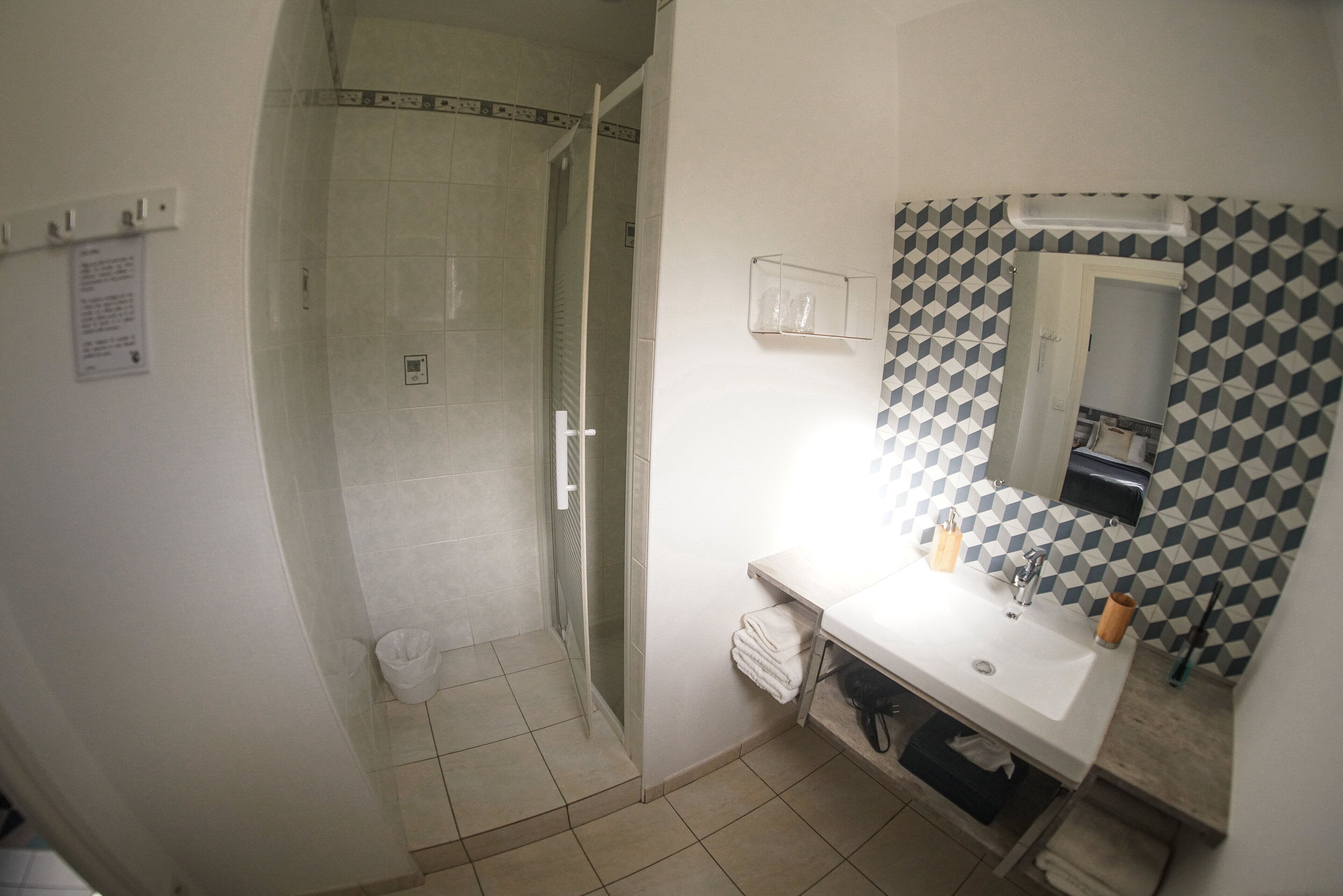 Een badkamer met een douche, wastafel en spiegel.