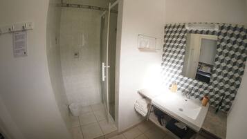 Een badkamer met een douche, wastafel en spiegel.
