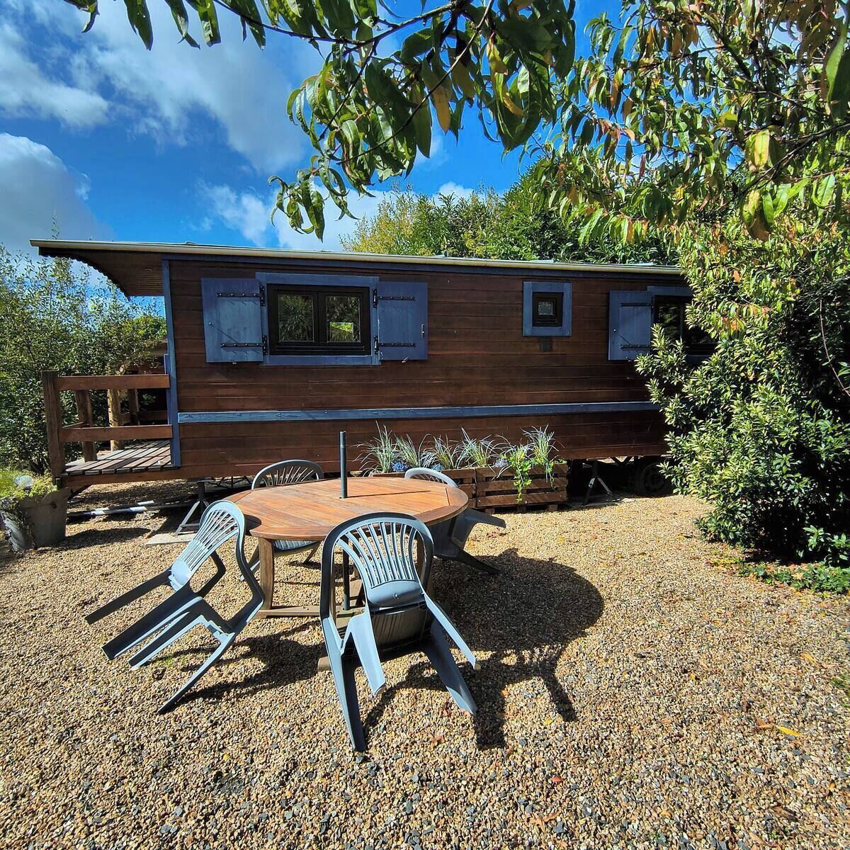 A wooden cabin with a deck, a round wooden table, and four chairs.