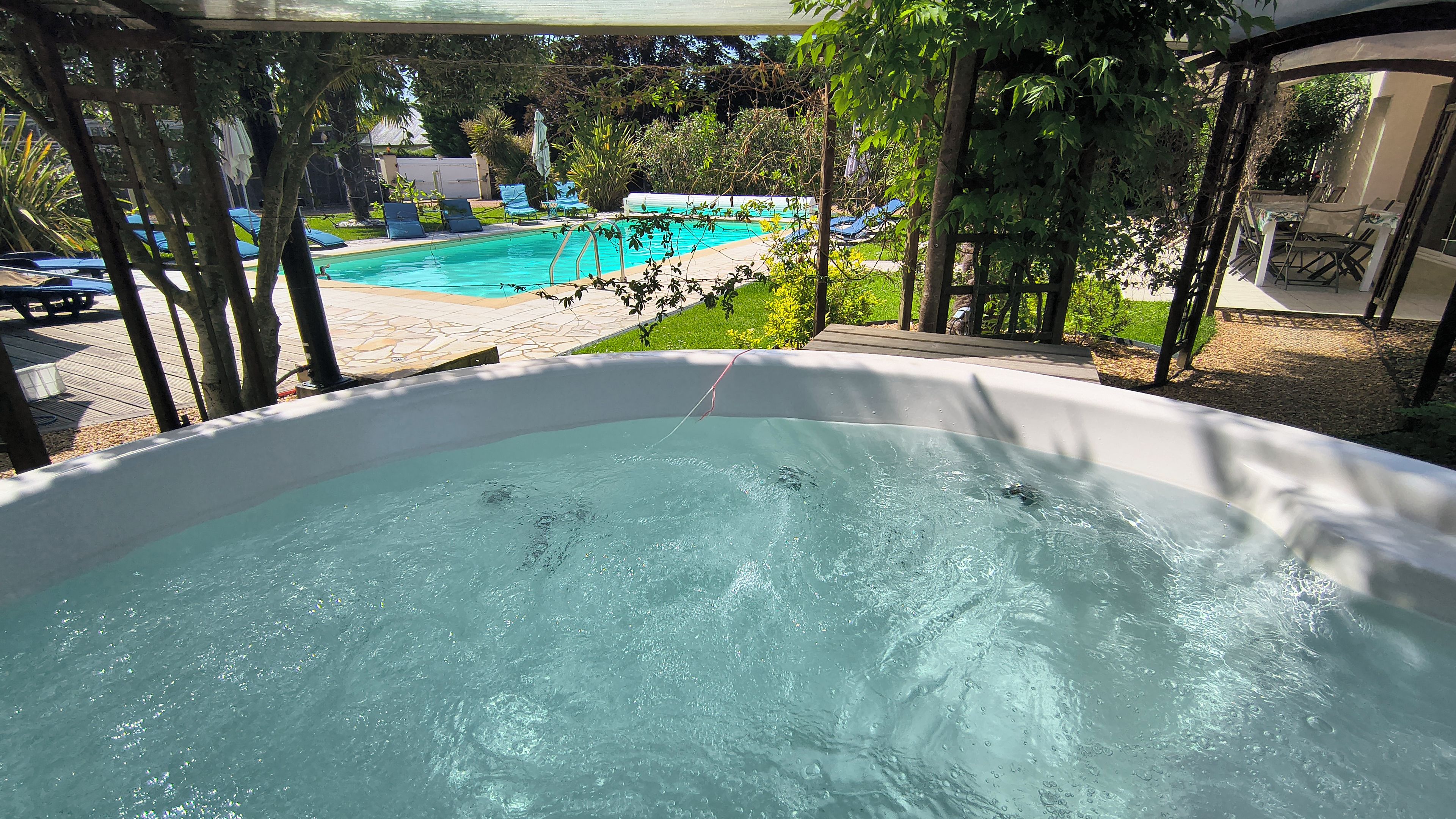 Un jacuzzi con vista a una piscina y sillas de descanso.