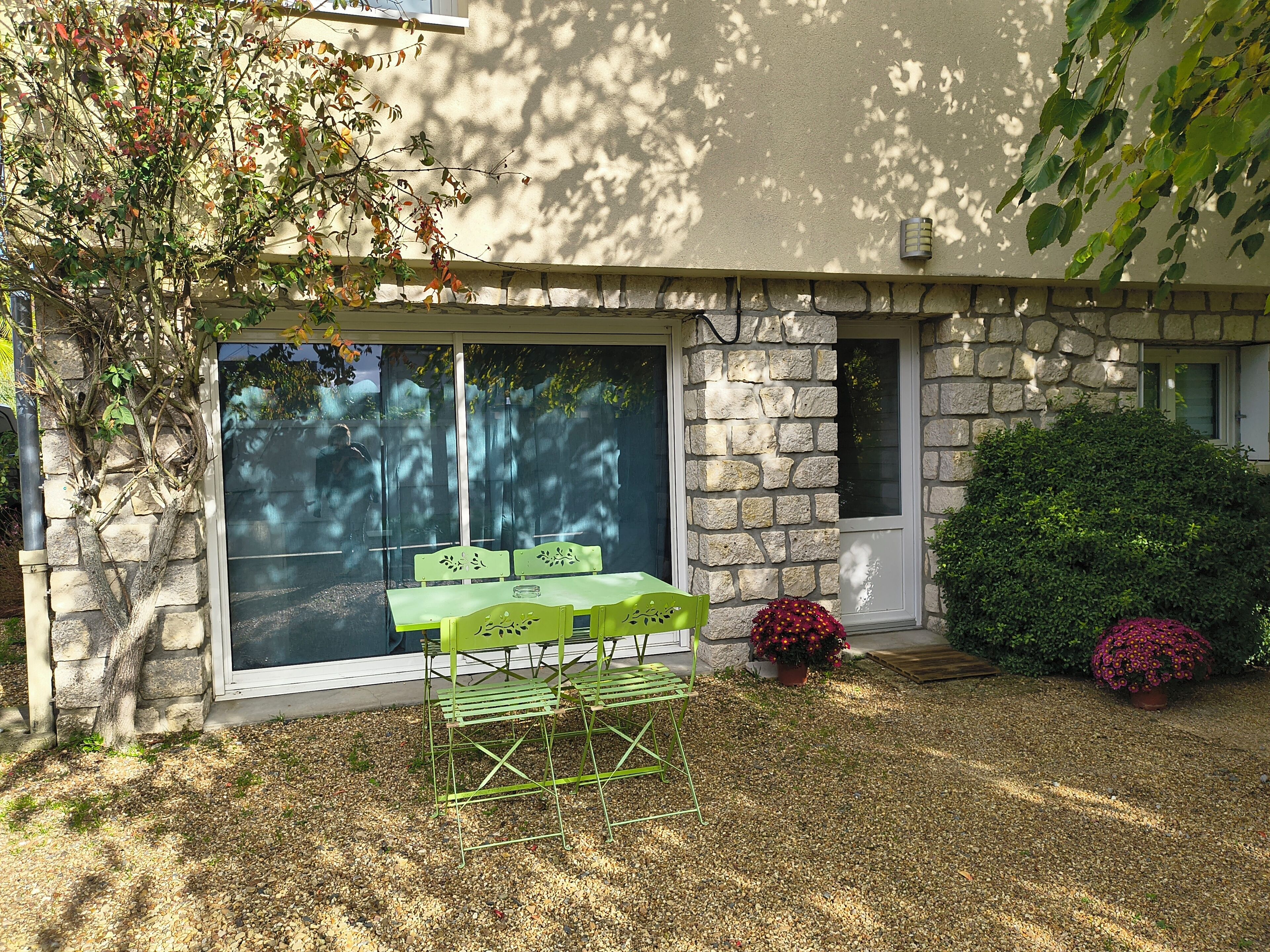 A patio with a table and chairs, a stone wall, and a small garden with a potted plant.