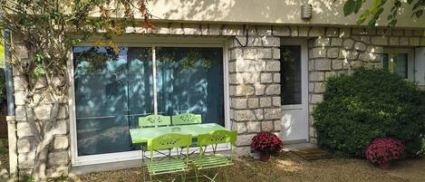 A patio with a table and chairs, a stone wall, and a small garden with a potted plant.