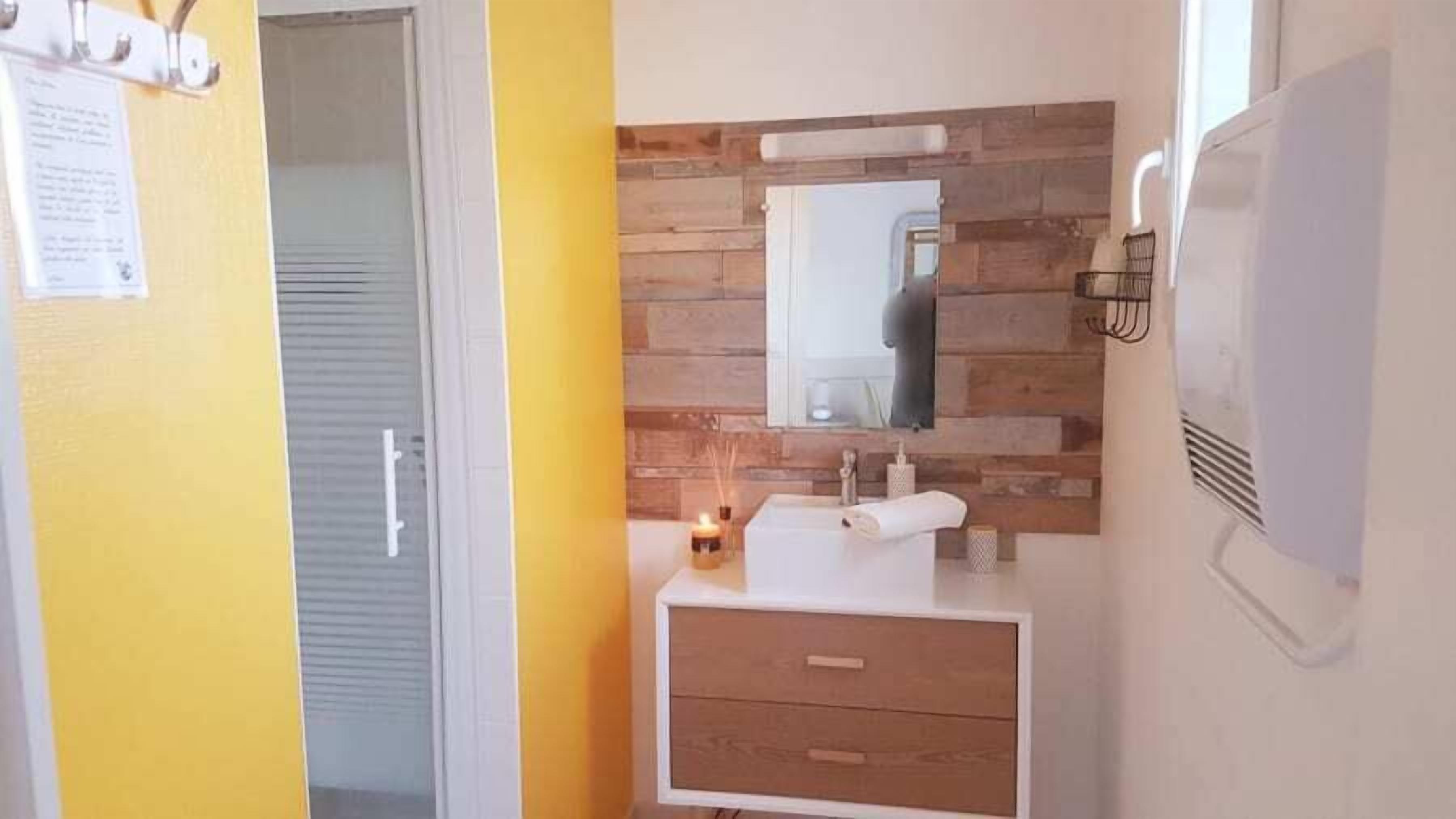 A bathroom with a wooden wall, a mirror, a sink, and a towel.