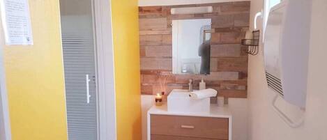 Un baño con pared de madera, un espejo, un lavabo y una toalla.