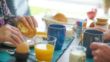 Ein Frühstückstisch mit einem Croissant, Orangensaft und verschiedenen Tassen.