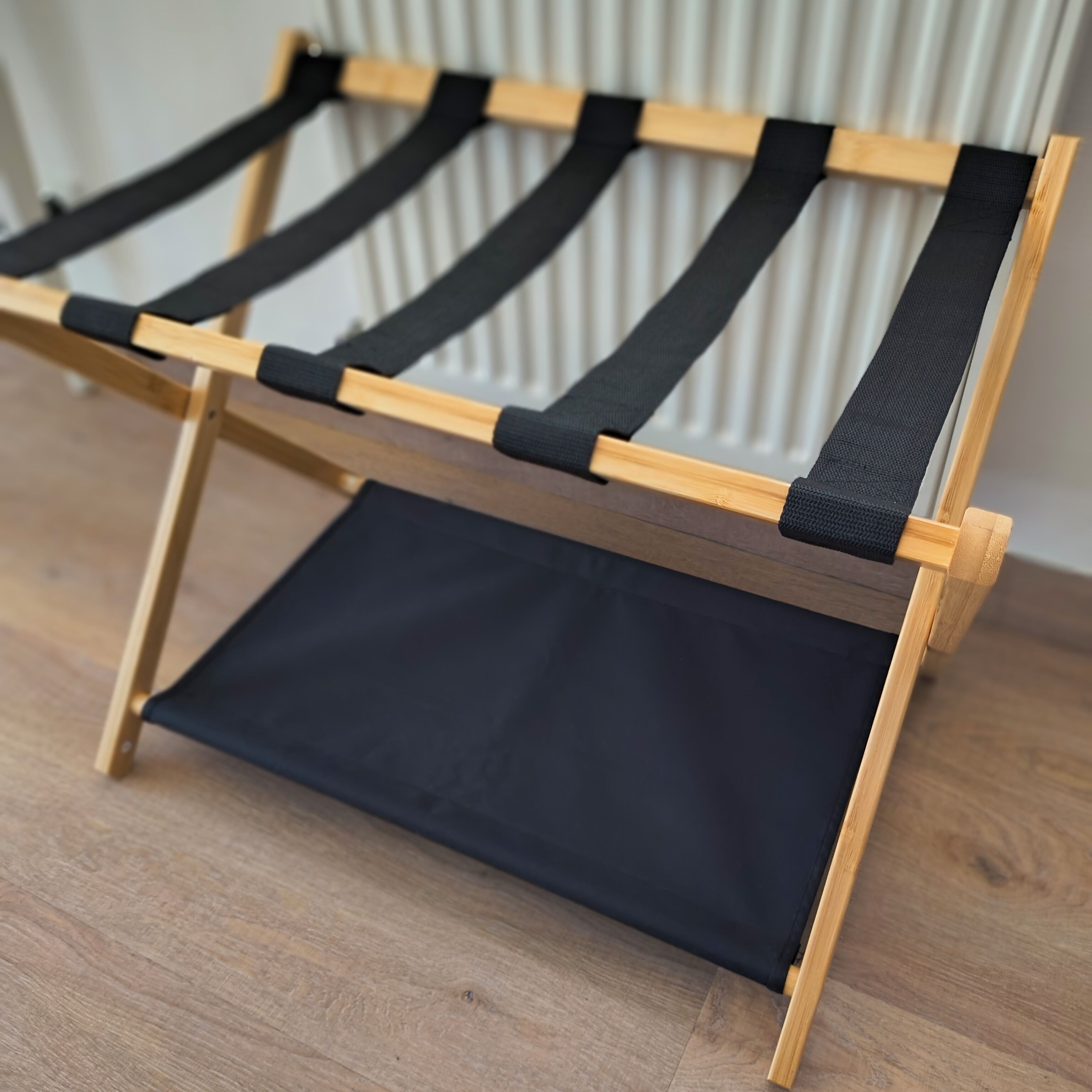 A wooden floor with a black canvas hammock.