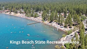 A coastal area with a pier, beach, and forested hills.