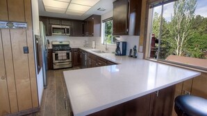 A modern kitchen with wooden cabinets, a large island, and a view of the outdoors.