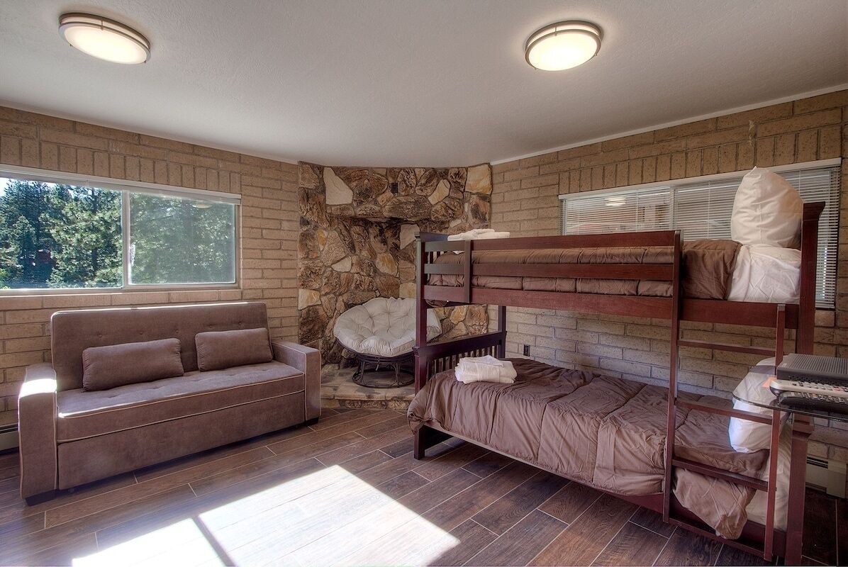 A room with a bunk bed, a sofa, and a stone wall.