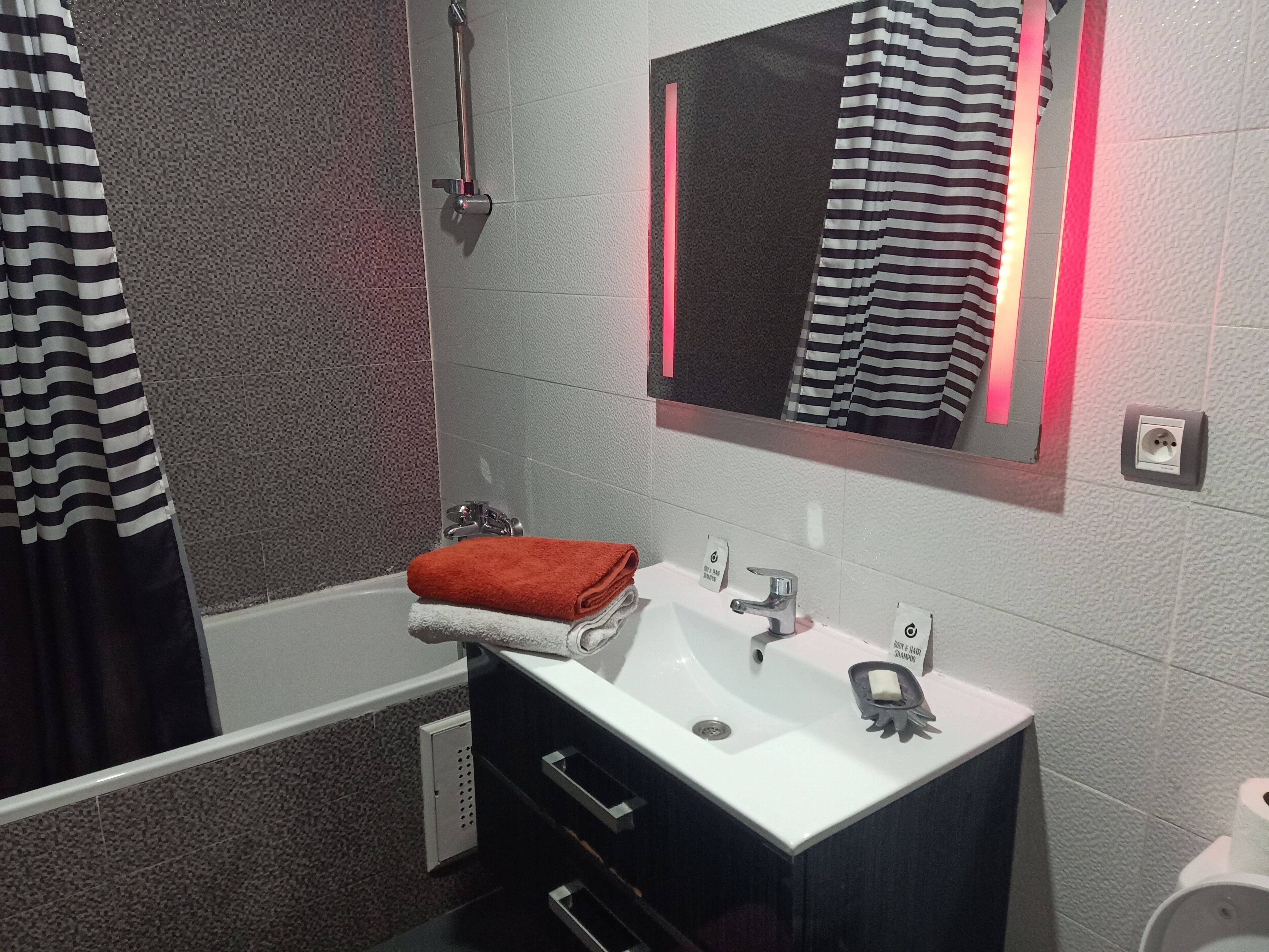 A bathroom with a white sink, a mirror, a towel, and a shower curtain.