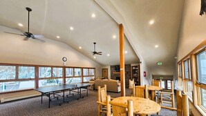 A spacious indoor area with multiple tables and chairs, large windows offering views of a snowy landscape, and a ceiling fan. - Cartwright Corner Condo 4 Bedroom Townhouse by RedAwning (Incline Village)
