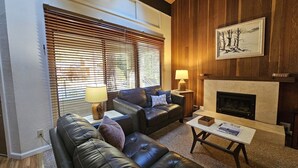 A living room with a fireplace, leather sofas, and wooden paneling. - Cartwright Corner Condo 4 Bedroom Townhouse by RedAwning (Incline Village)
