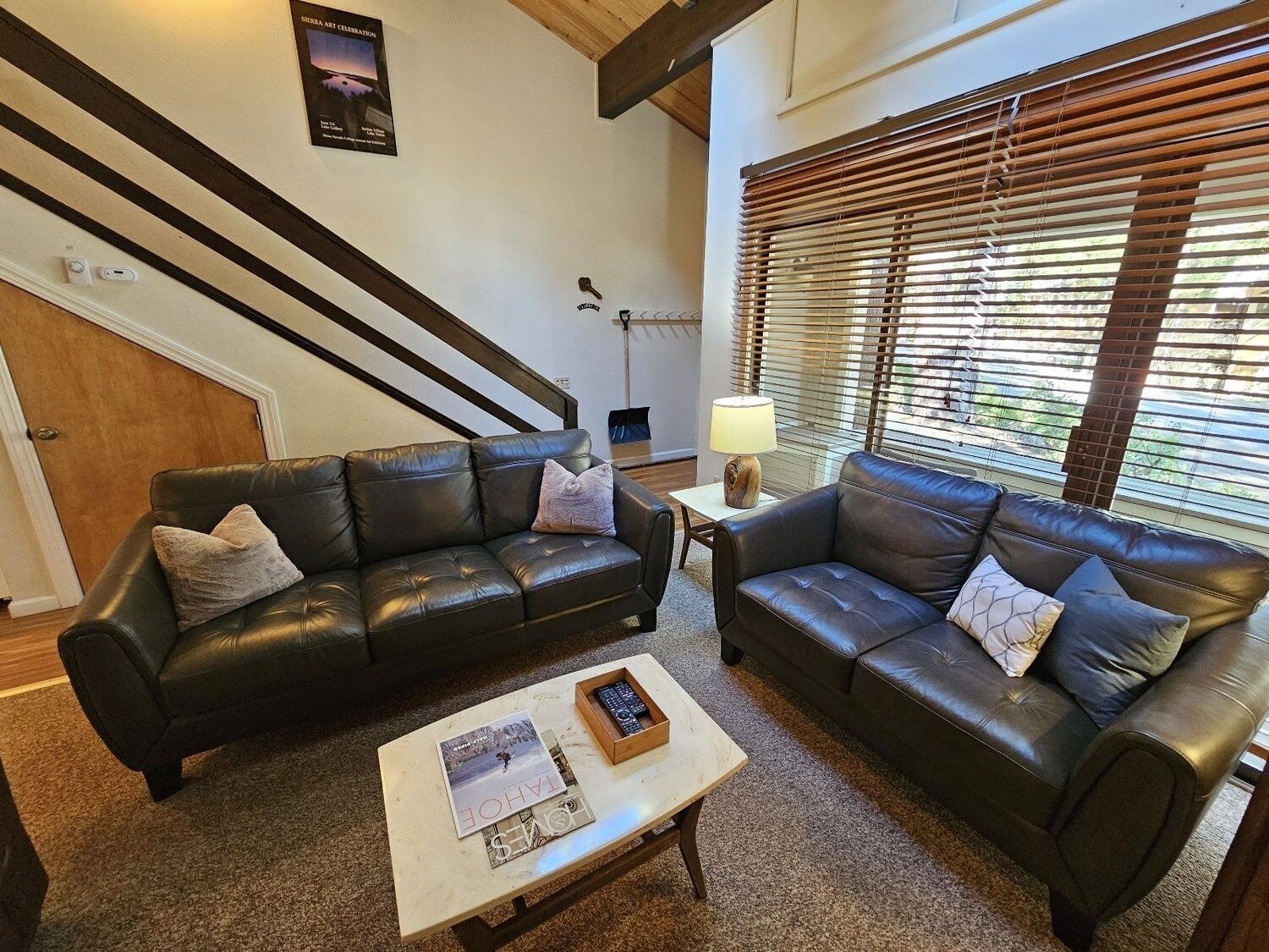 A living room with two black leather sofas, a coffee table with magazines, and a lamp.