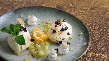 Un plato de postre con helado y guarniciones de fruta.