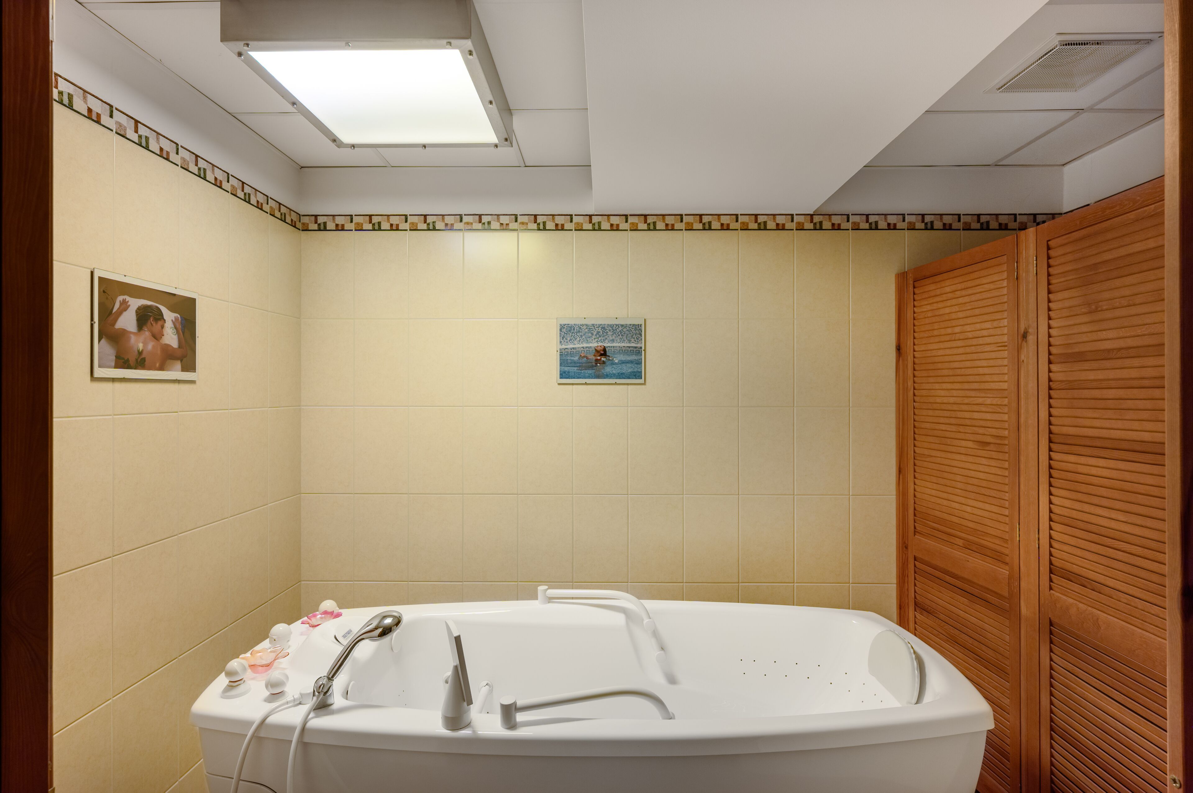 A bathroom with a bathtub, a shower, and a wooden wardrobe.