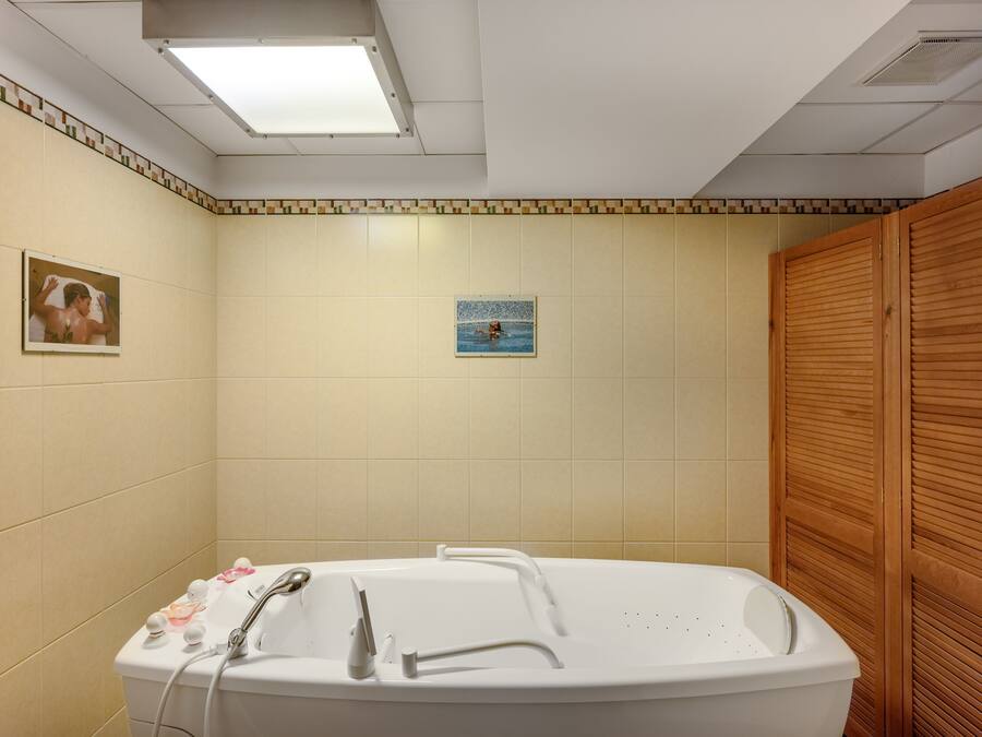 A bathroom with a bathtub, a shower, and a wooden wardrobe.