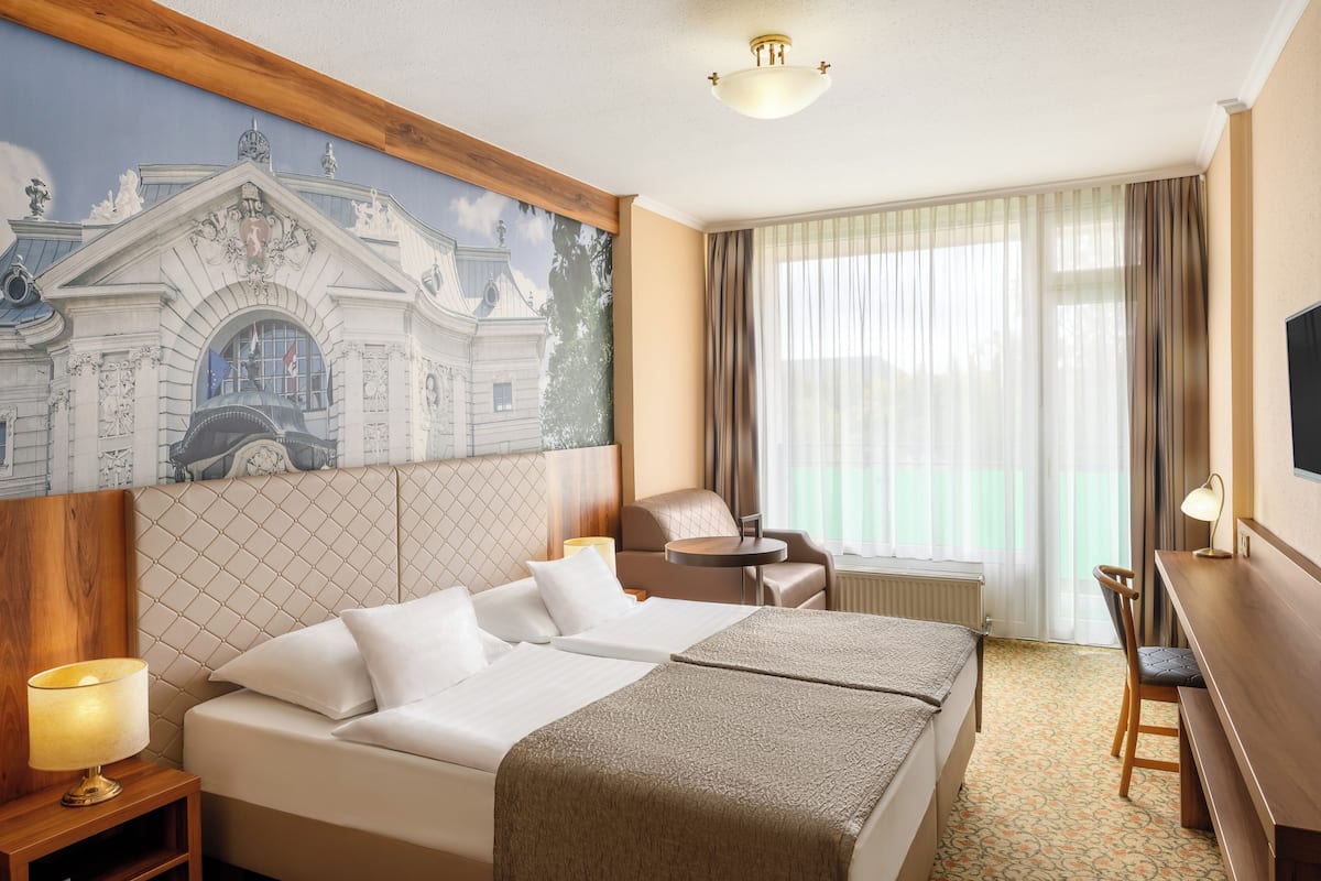 Una habitación de hotel con una cama grande, un escritorio, una silla y un televisor.