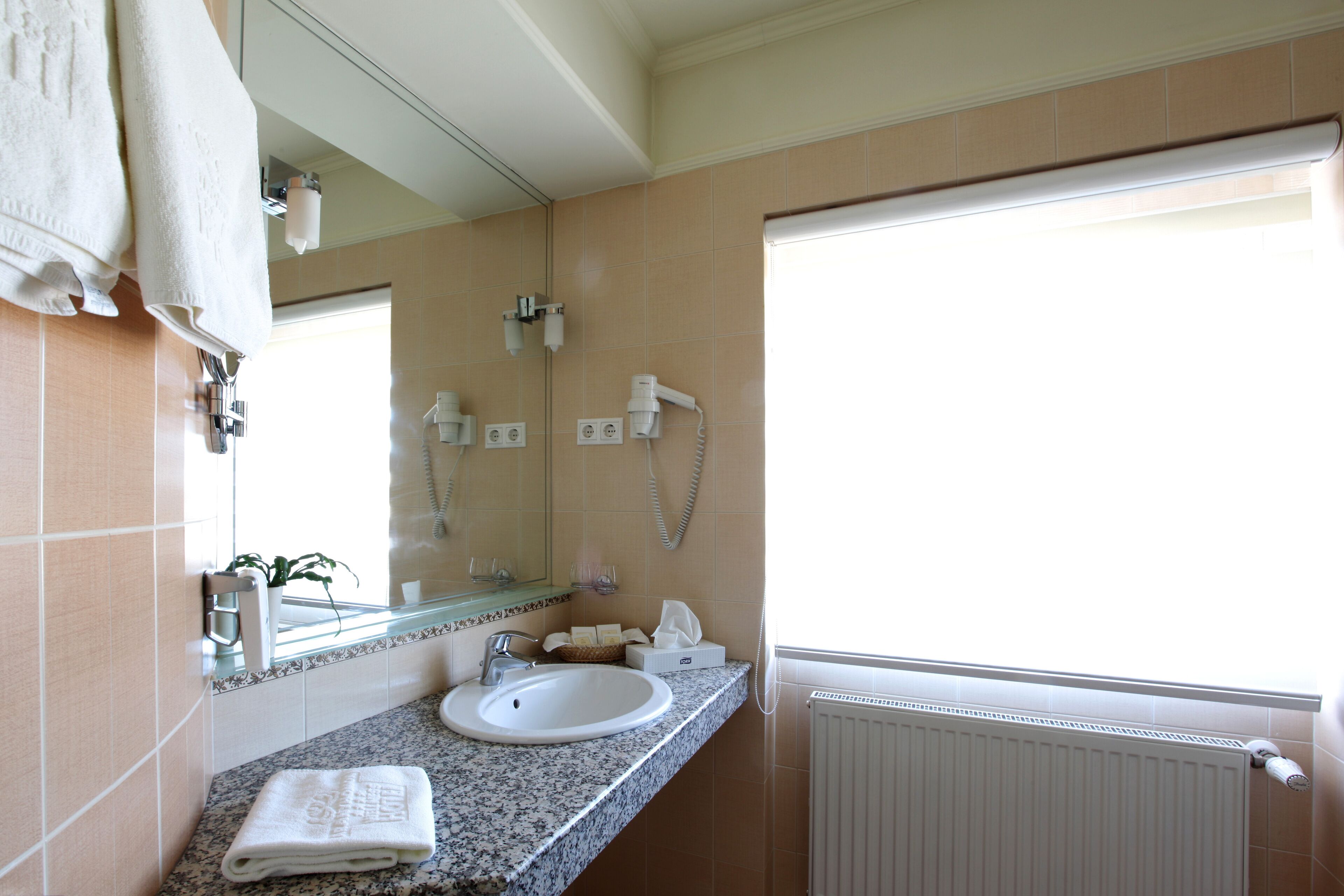 A bathroom with a sink, towel rack, mirror, and a window with a view.