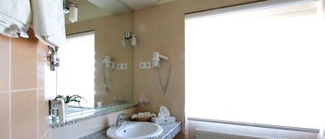 A bathroom with a sink, towel rack, mirror, and a window with a view.