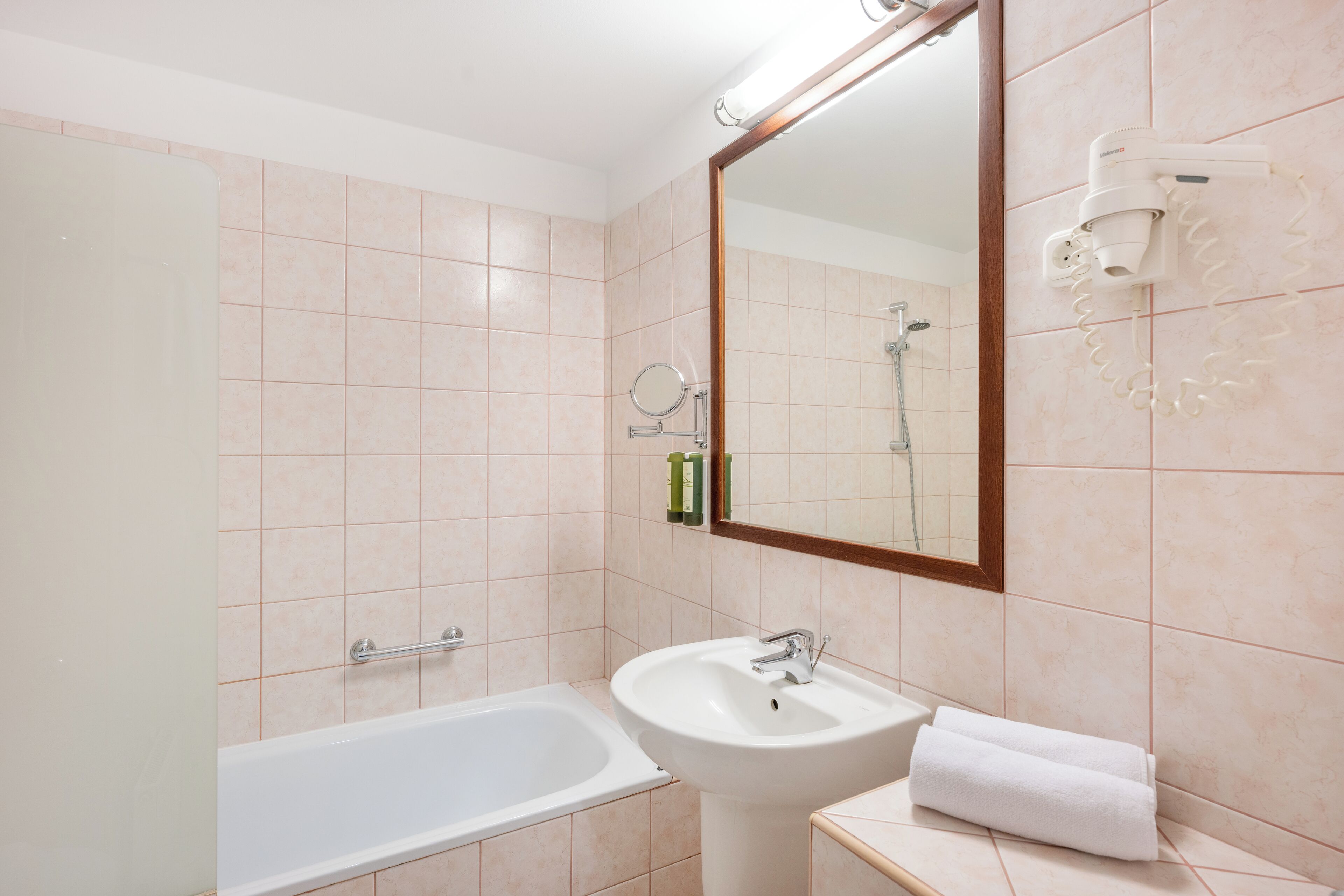 A bathroom with a bathtub, sink, and a mirror.