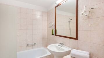 A bathroom with a bathtub, sink, and a mirror.
